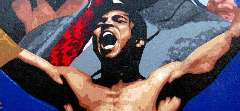 Mural art painting of hall-of-fame boxer and social activist Muhammad Ali, with his arms raised and shouting in celebration.